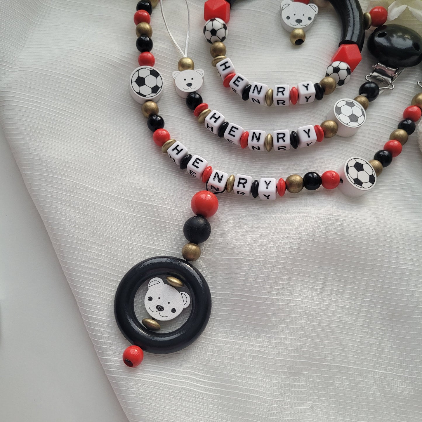 3tlg Set Schnullerkette Kinderwagenkette Greifling Fussball schwarz rot gold