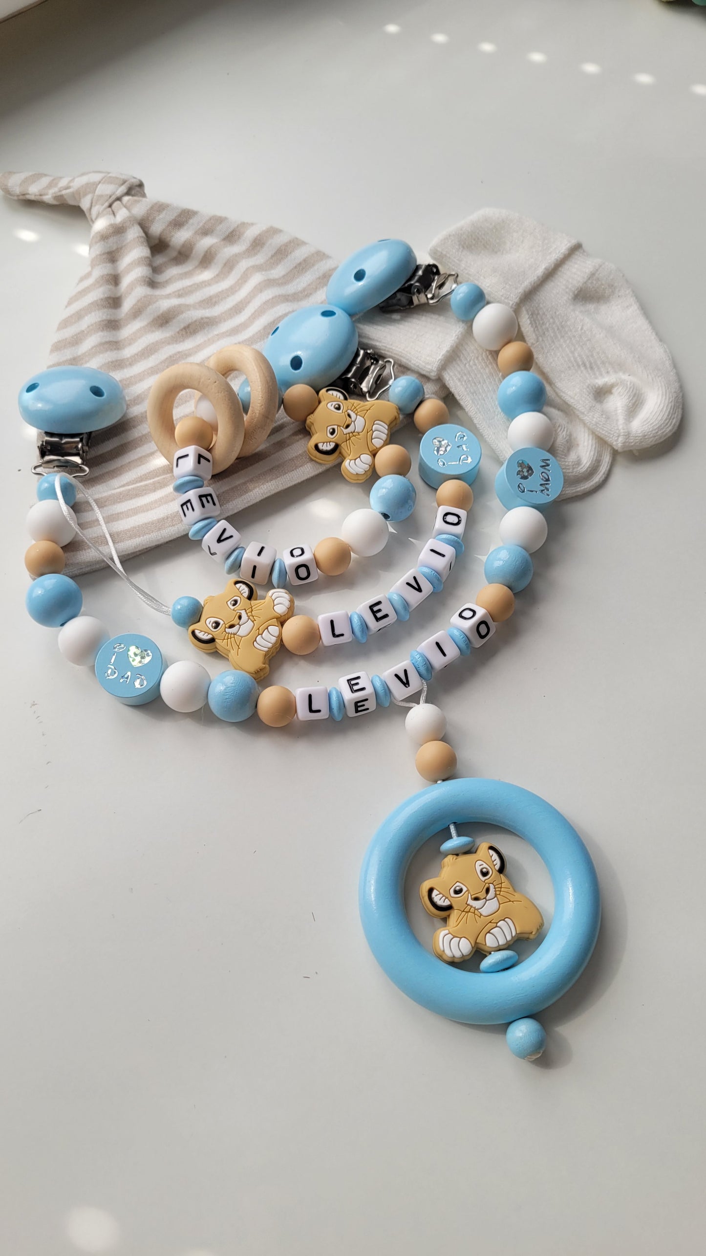 3tlg. Set Schnullerkette Kinderwagenkette & Beissring mit Namen Löwe & i love Mom und Dad blau weiss beige
