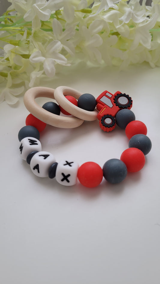 Greifring personalisiert mit weissen Silikonbuchstaben, rot grauen Silikonperlen und Traktor Motiv aus bpa freien Silikonmaterial 2 Holzringe